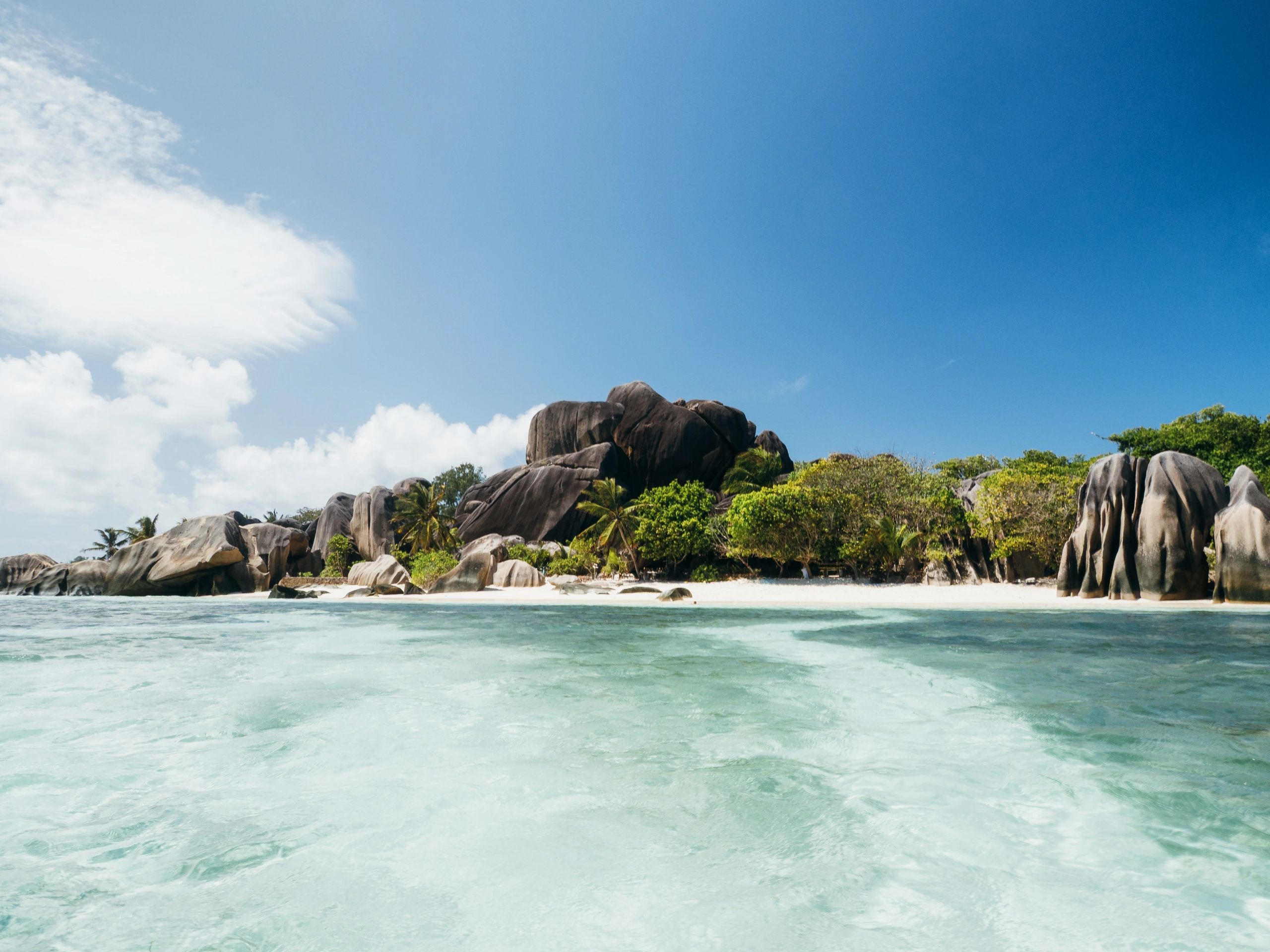 Peaceful tropical shoreline with clear water and natural rock formations, evoking calm and stress relief